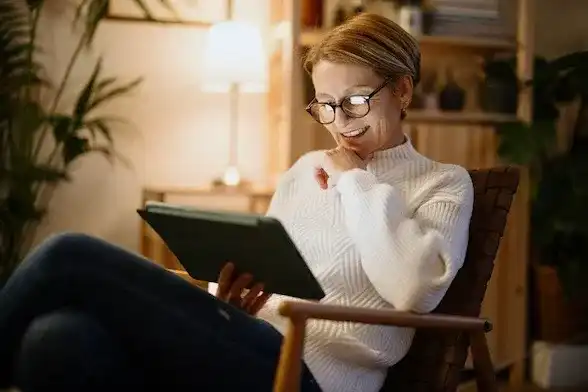A mature woman reads on a digital tablet at night