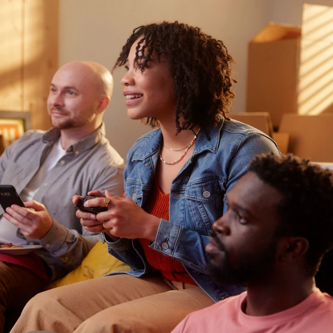 Three people are sitting, in that Lady is playing online game  and remaining  two people are watching  it.