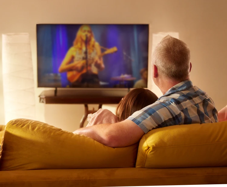 Dad and daughter enjoy streaming TV on their couch with Brightspeed fiber internet.