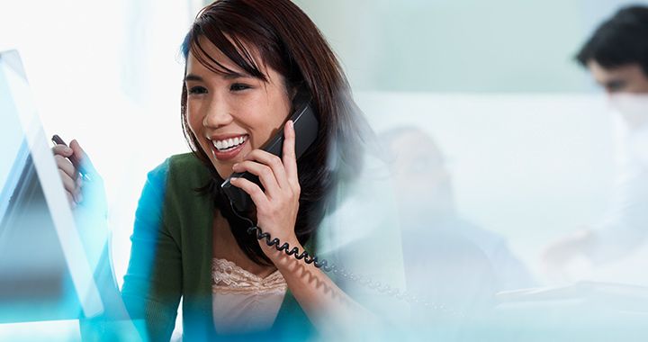 Business woman sitting in a brightly lit room talking on a phone