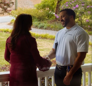 A man and woman shaking hands on a porch after a successful Brightspeed Internet installation.