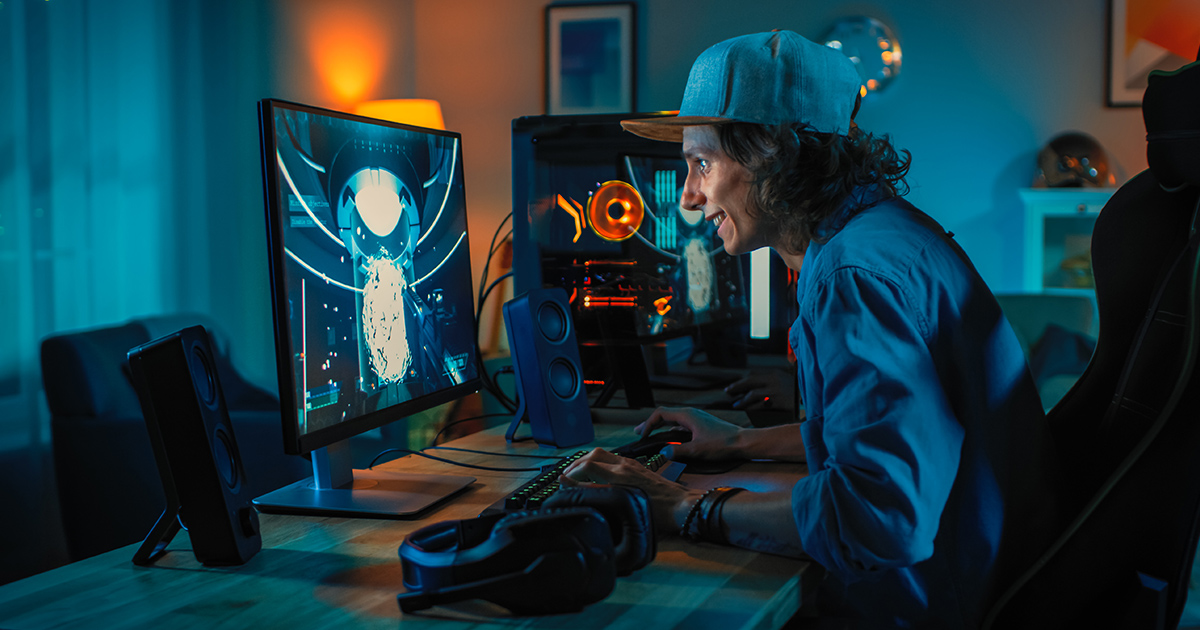 A young man in a baseball hat smiles while gaming online