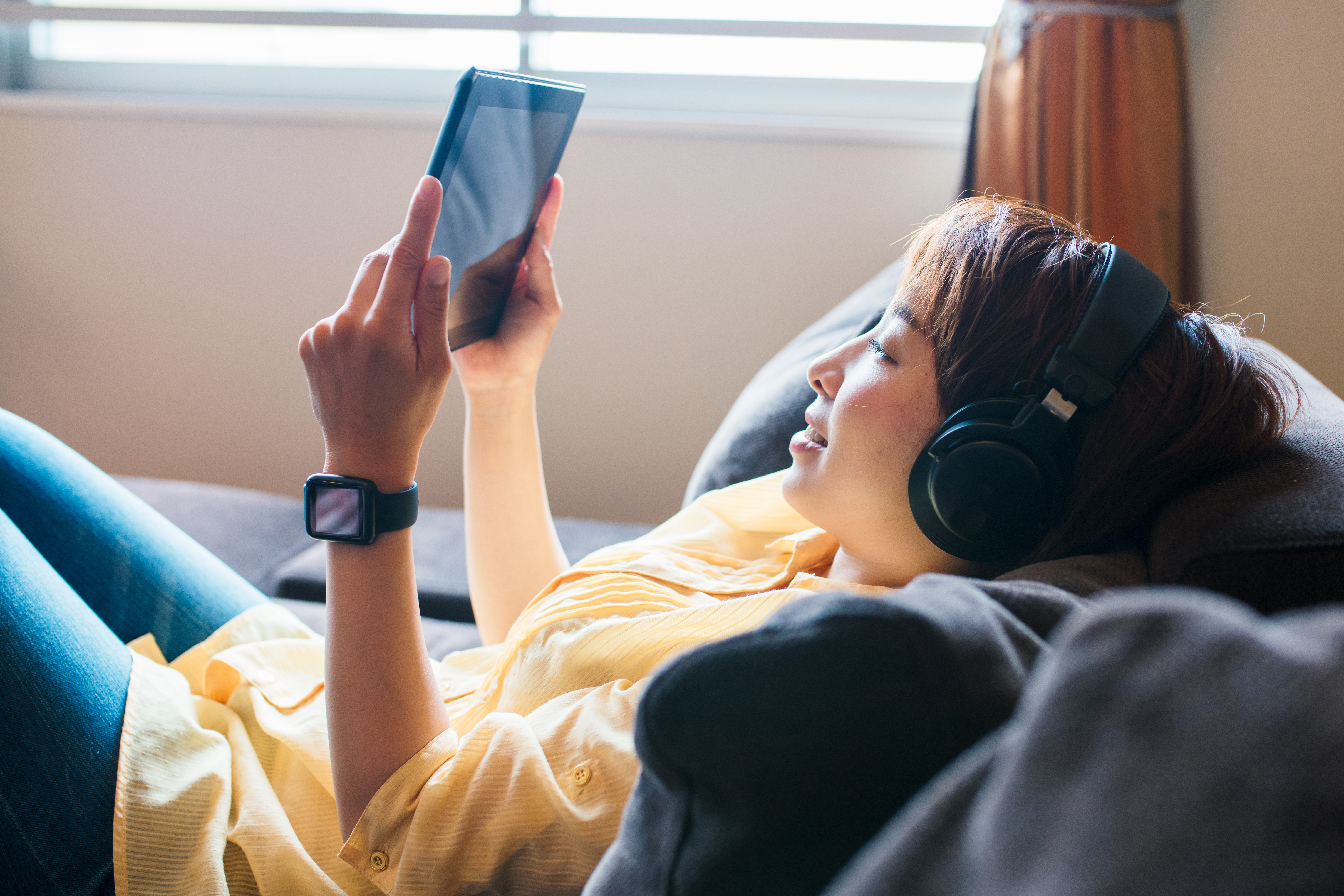 A young woman with headphones looking at a tablet.