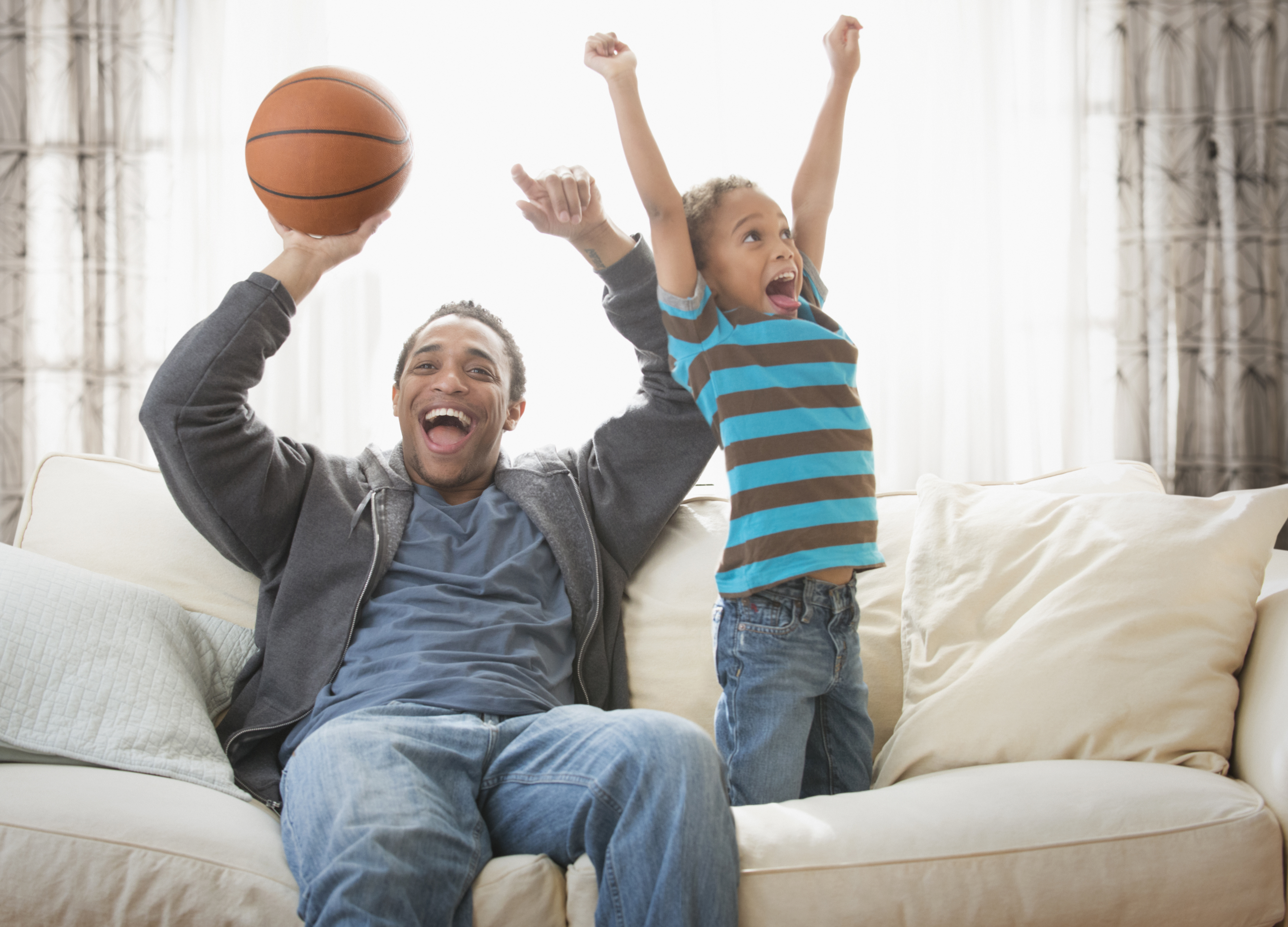 A father and daughter holding a basketball and cheering.